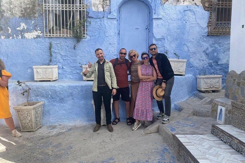 Un grupo de personas posando frente a un edificio azul con una puerta y escalones. 2