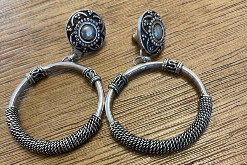 A pair of silver hoop earrings with a textured design and a round, faceted gemstone. 1