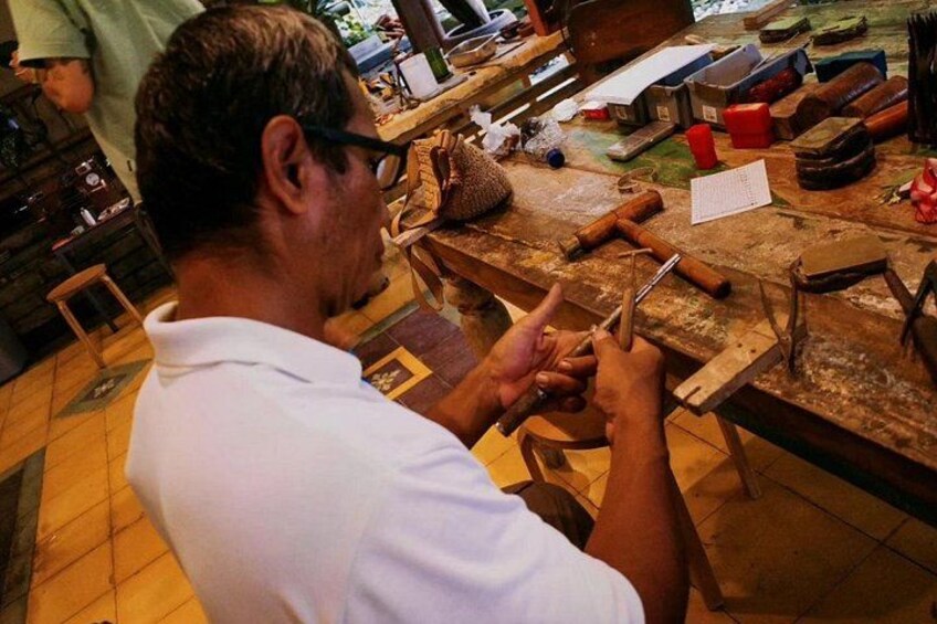 A person working with tools on a wooden table in a workshop. 2
