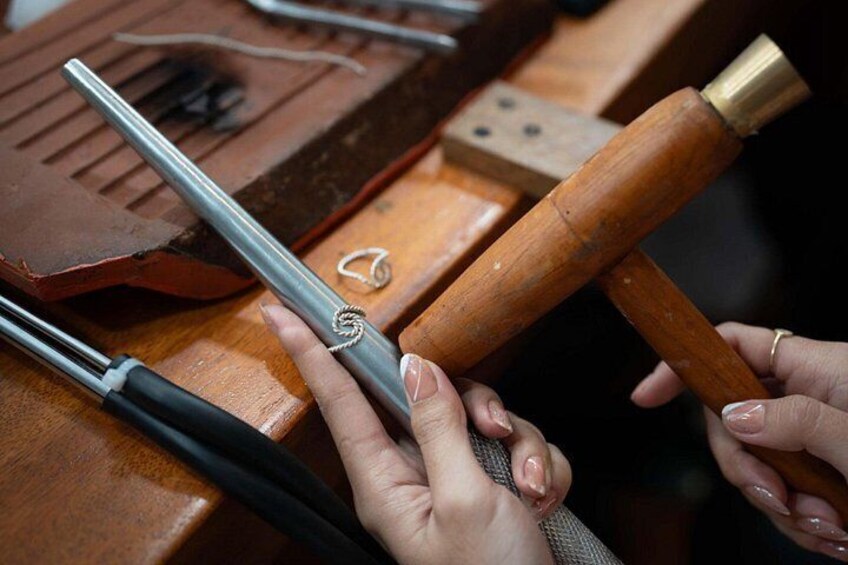 Hands holding a metal tool and a wooden mallet. 5