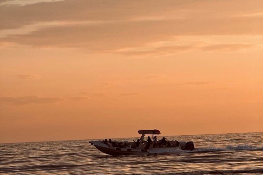 A boat with passengers on a body of water during sunset. 2