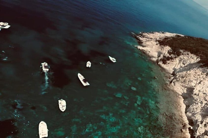 A coastal area with clear turquoise waters and several boats anchored near the shore. 5