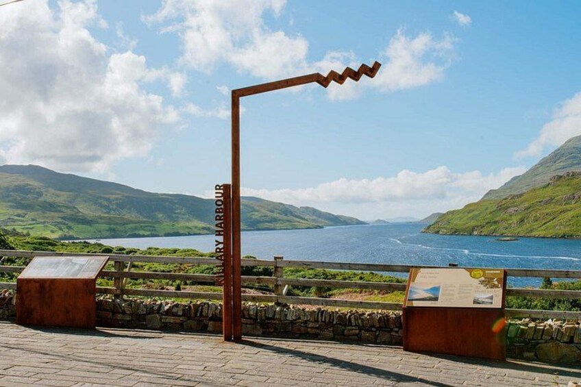 A scenic viewpoint with a metal sculpture, a stone wall, and a placard reading 'Mary Harbour.' 3