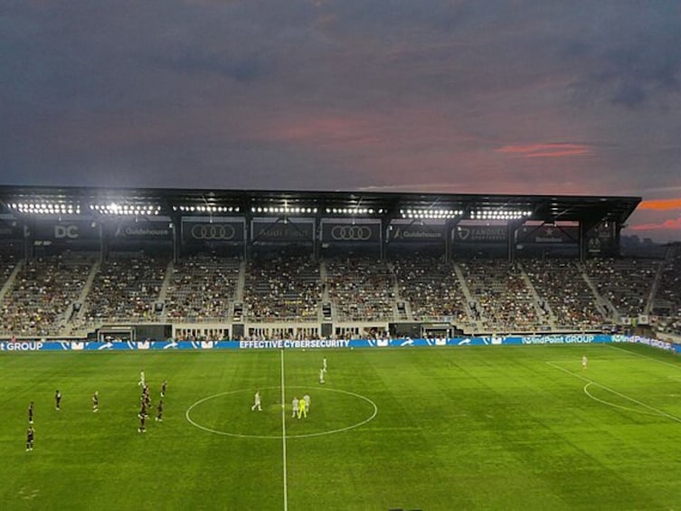 Et stadion med en fodboldbane, tomme tribuner og reklamebannere. 2