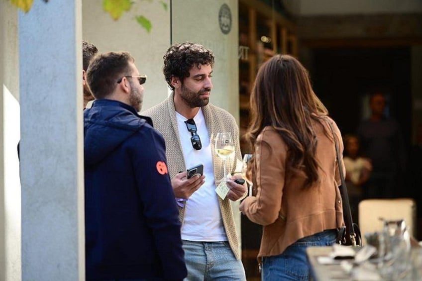 A group of people standing outside a building, some holding drinks. 2