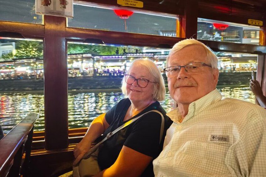 Couple enjoying the Singapore River Cruise at night with the city lights reflecting on the water. 2