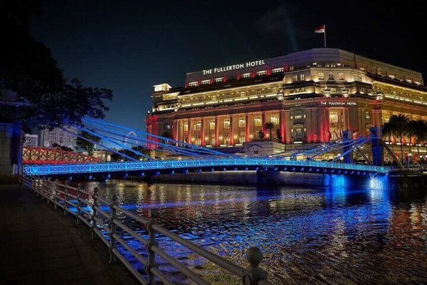 The Fullerton Hotel with illuminated blue lights on a bridge over water. 4