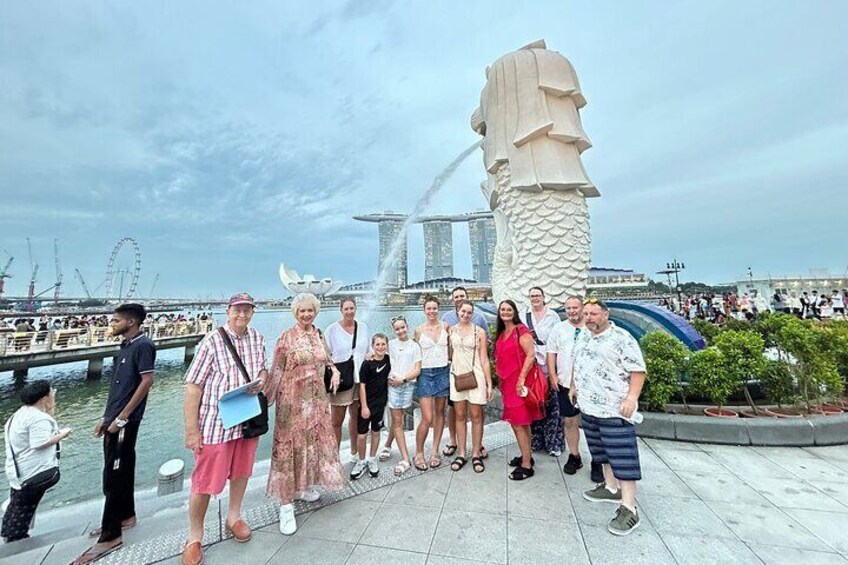 Un grupo de personas posando frente a una gran escultura y un edificio moderno. 5