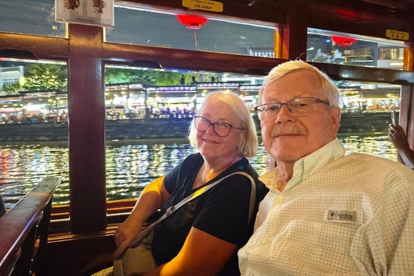 Couple enjoying the Singapore River Cruise at night with the city lights reflecting on the water. 3