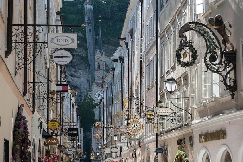 Una calle estrecha flanqueada por edificios, faroles decorativos y varios letreros de tiendas. 4
