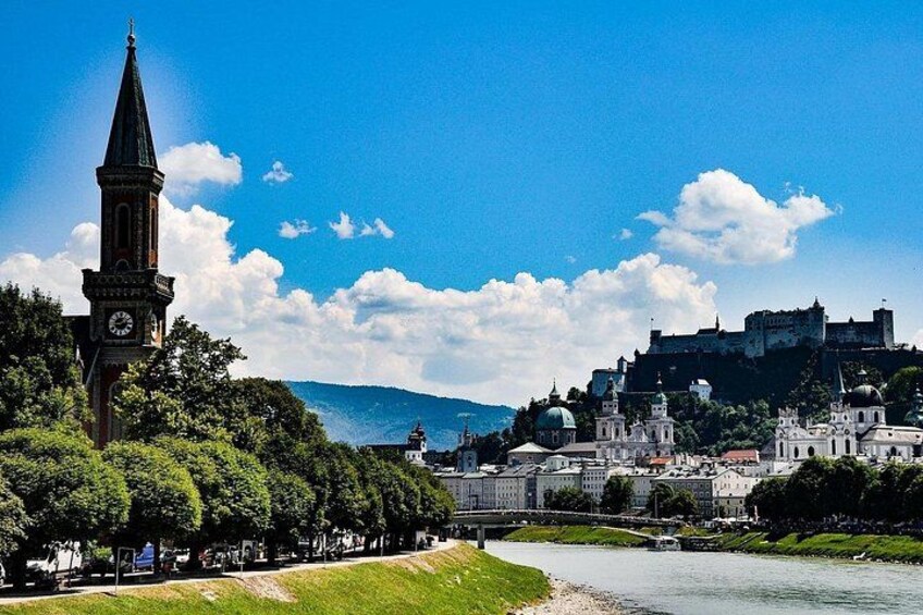 Un pueblo histórico con una imponente torre del reloj, un río y un castillo en una colina. 2