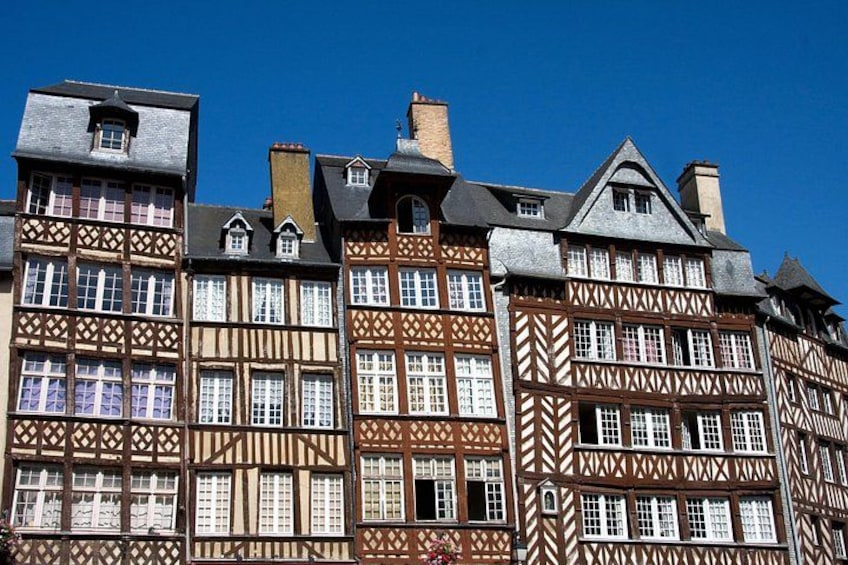 A row of half-timbered buildings with multiple windows and chimneys. 1