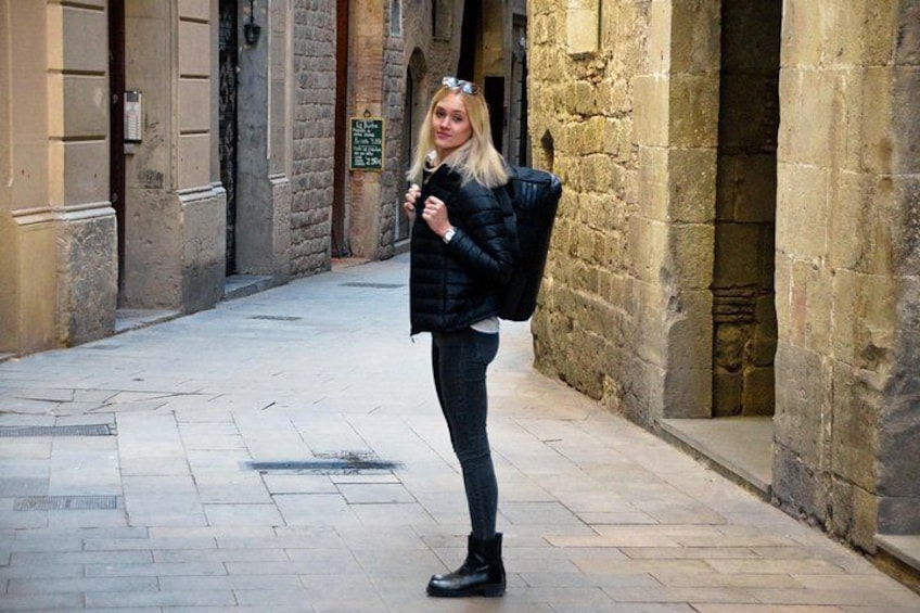A person standing in a stone-paved alleyway with historical buildings on either side. 3