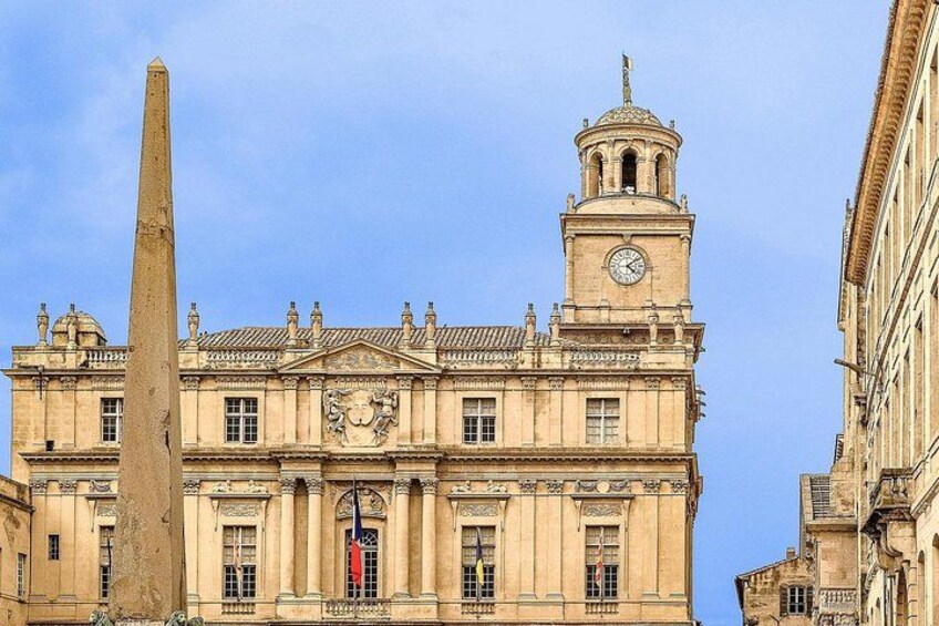 A historic building with a clock tower, a prominent obelisk, and classical architecture. 1