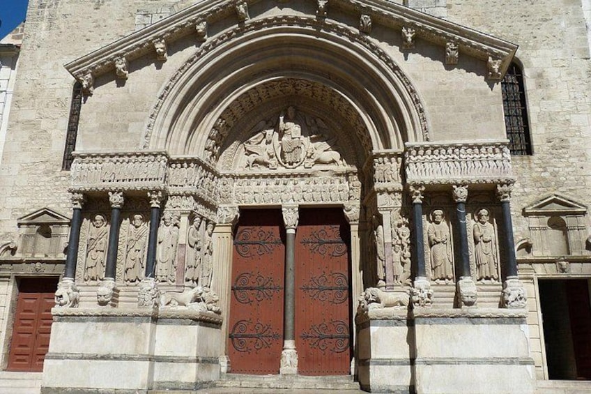 A stone building with a large arched entrance, detailed carvings, and a red door. 2
