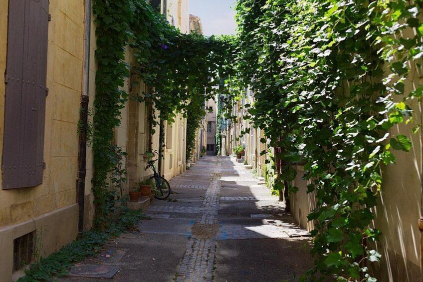 A narrow alley with buildings on either side, a bicycle parked on the left, and a cobblestone path. 5
