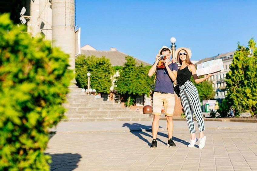 A couple taking a photo in a public square with a historic building in the background. 5