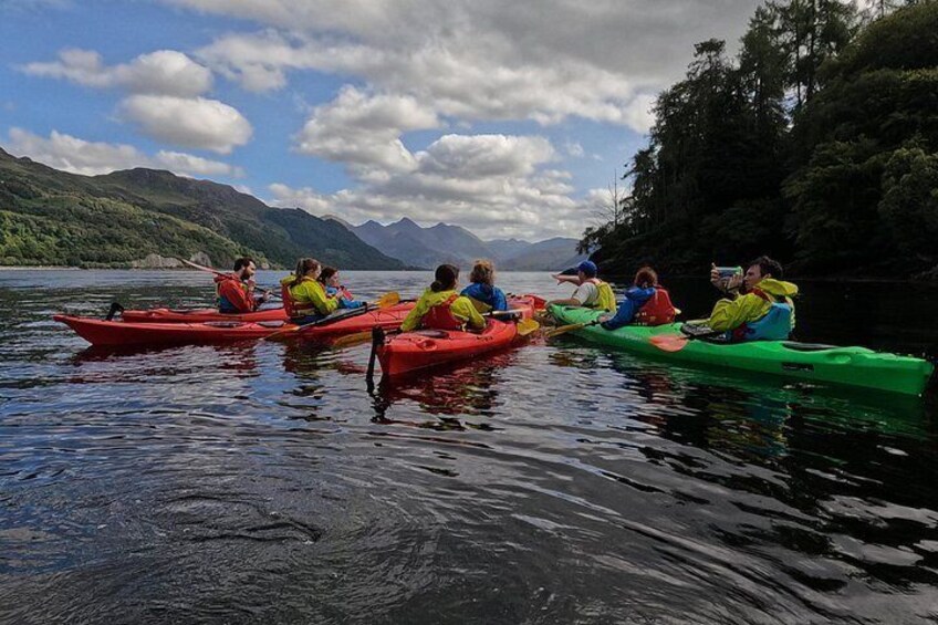 A group of people kayaking on a calm lake with mountains in the background. 3