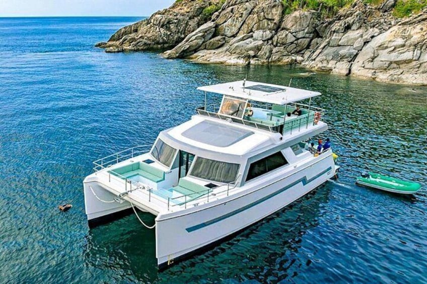 Un bateau blanc, doté d’une cabine et d’un moteur hors-bord vert, navigue sur une eau bleue et calme, près de côtes rocheuses. 5