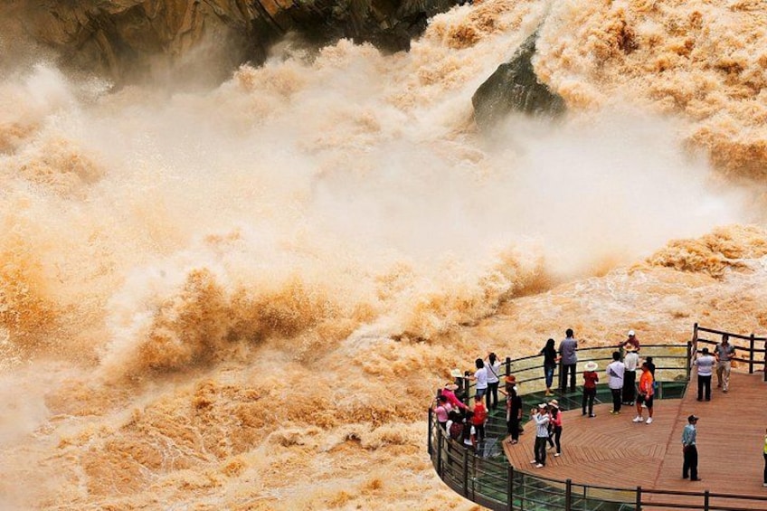 A turbulent river with people observing from a wooden viewing platform. 3