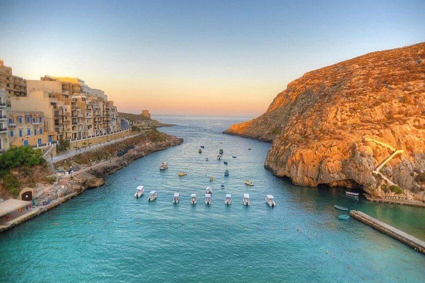 A coastal town with boats anchored in a bay, rocky cliffs, and buildings along the waterfront. 3