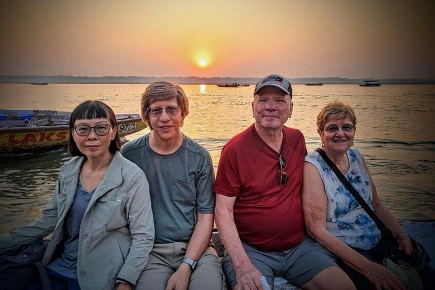 A sunset over a body of water with boats and a person in a red shirt. 3