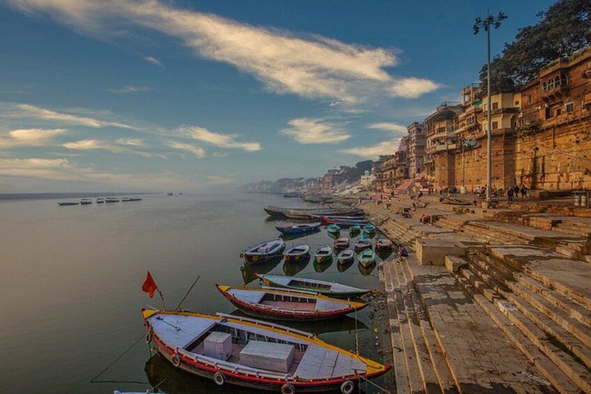 A riverside with boats docked, steps leading down to the water, and buildings along the riverbank. 2
