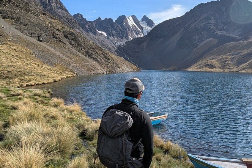 A person sitting on the shore of a lake with mountains in the background. 4