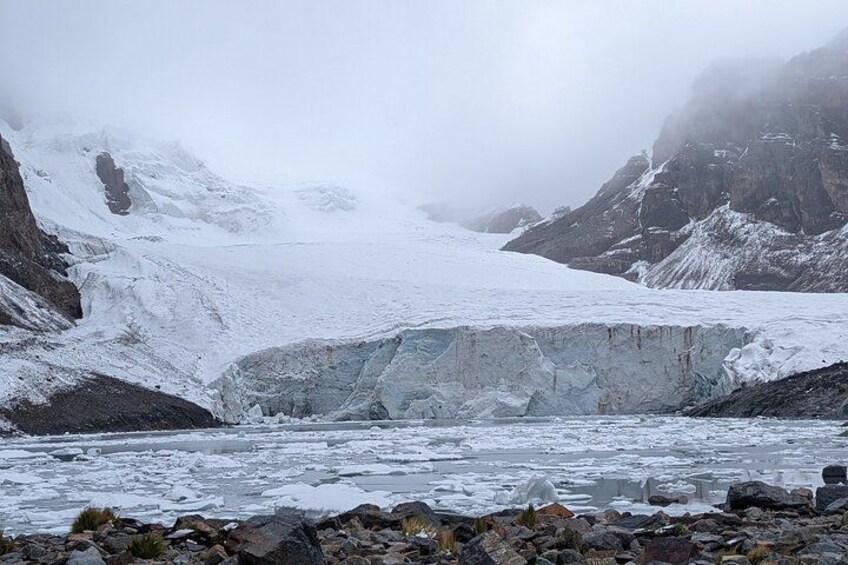 A glacier with a river flowing through it, surrounded by rocky terrain and mountains. 3