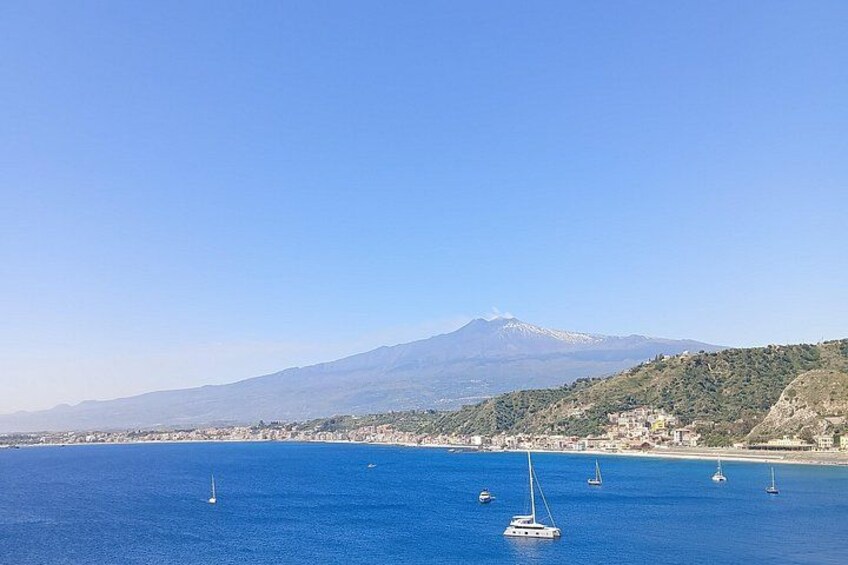Paisaje costero con una montaña al fondo, mar azul cristalino y varios veleros. 3