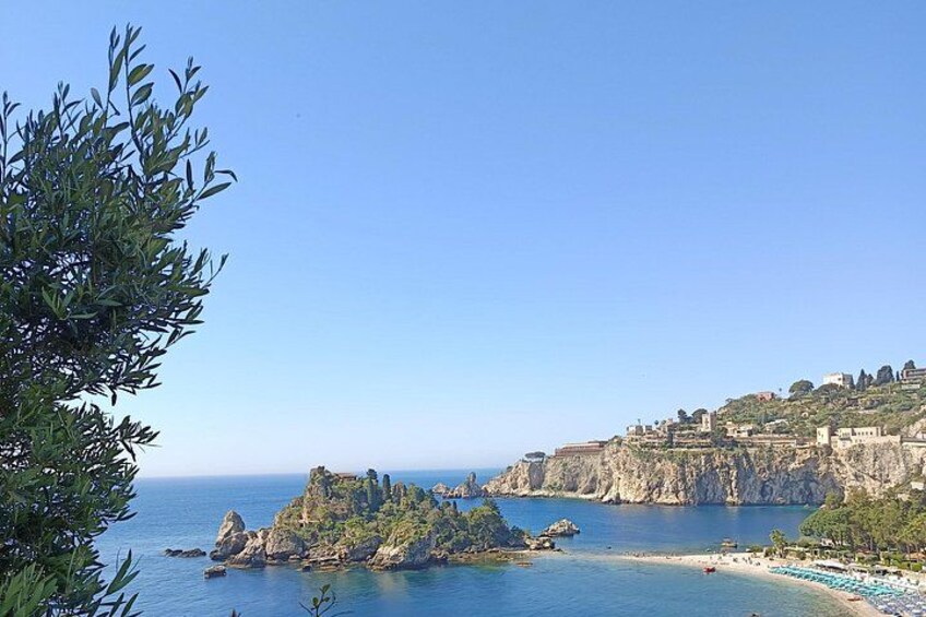 Paisaje costero con acantilados rocosos, una playa y una pequeña isla. 2