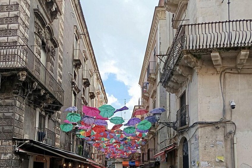 Una calle con edificios, sombrillas de colores y cielo despejado. 1