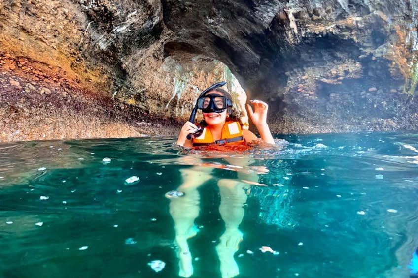 Une personne fait de la plongée avec tuba dans une eau d’un bleu limpide, avec une grotte rocheuse en arrière-plan. 1