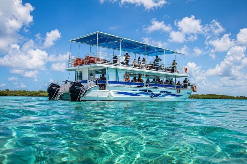 A boat with passengers, clear turquoise water, and a blue sky with clouds. 2