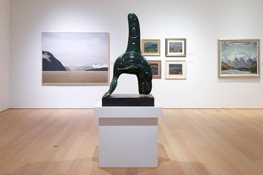 A sculpture in an art gallery with framed paintings on the walls. 4
