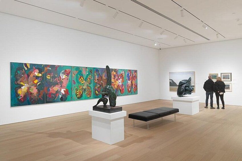 An art gallery with abstract paintings, sculptures, and a wooden floor. 2
