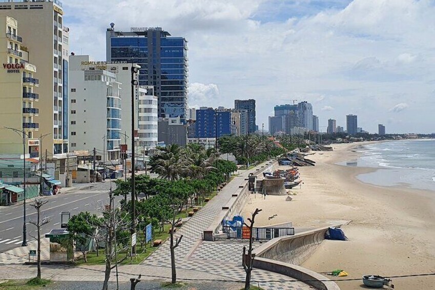 A beach with a cityscape in the background, including a hotel and tall buildings. 5
