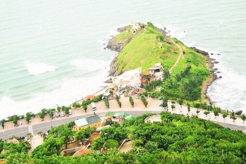 A coastal landscape with a grassy hill, a road, and a small building. 4