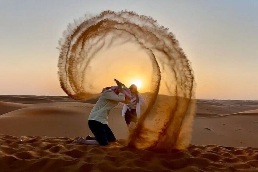 Two people in a desert with a large sand dune formation. 3