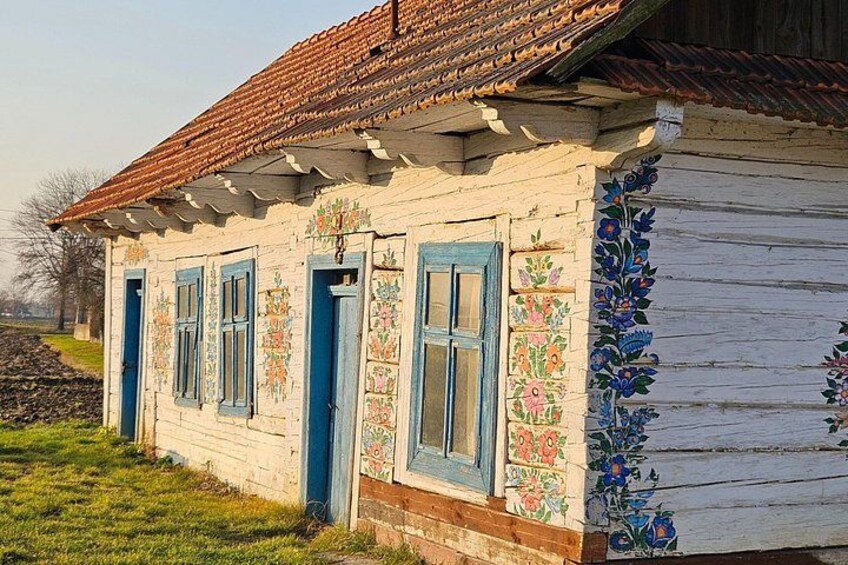 Ein traditionelles Holzhaus mit bunten floralen Mustern und blauen Fensterläden. 2