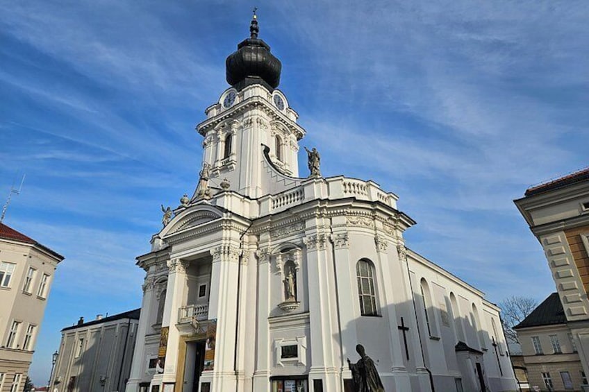 A white church with a large dome and statues, surrounded by other buildings. 1