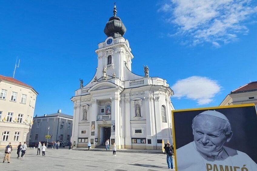 Un edificio storico con una cupola e una statua in cima, circondato da una piazza affollata di persone. 1