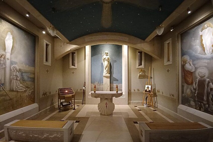 Een kerkinterieur met een centraal beeld, schilderijen aan de muren en een sterrenhemel als plafond. 5