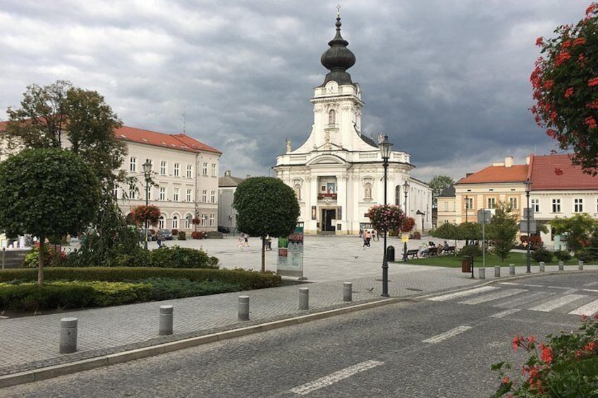 A city square with a prominent church, a paved road, and surrounding buildings. 2
