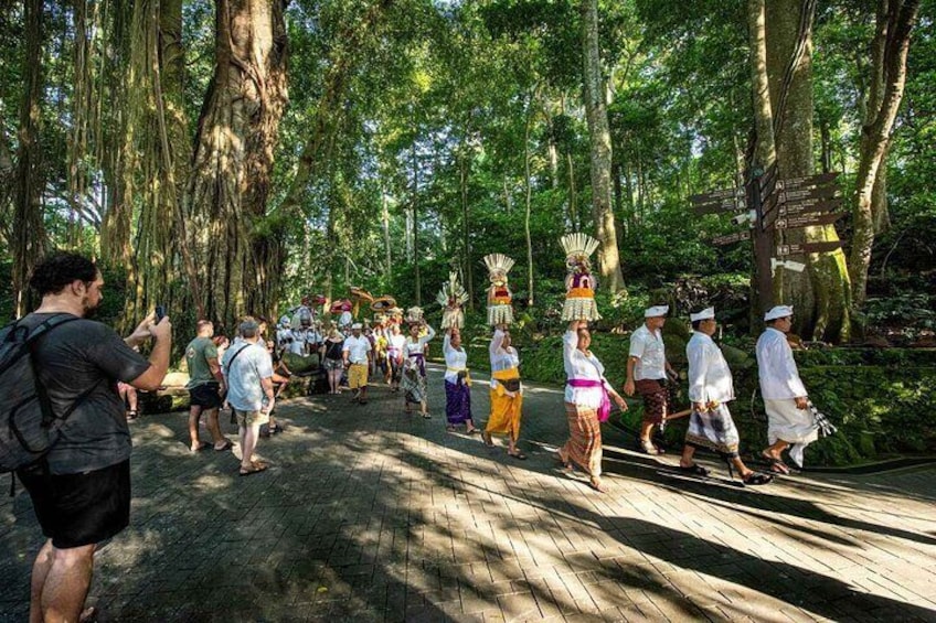 Un grupo de personas vestidas con trajes tradicionales caminando por un sendero de madera en un bosque. 1