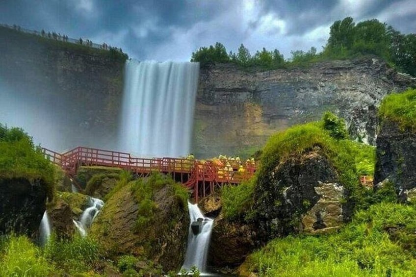 A waterfall, a red bridge, and lush greenery. 1