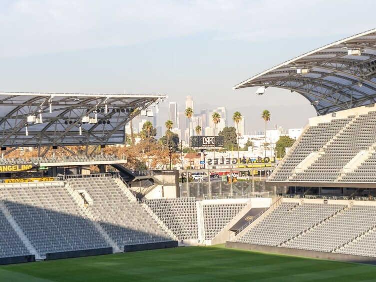 A large stadium with empty stands, a city skyline in the background, and a clear sky. 5