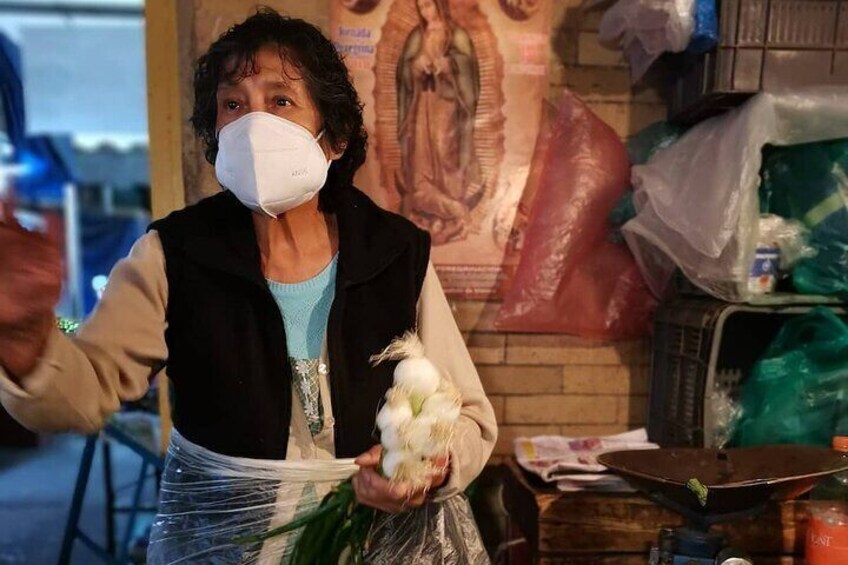 A person holding a white bird, standing in front of a wall with a religious mural. 3