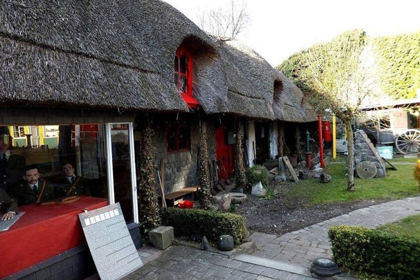 A traditional thatched-roof house with a red door and a red awning. 2