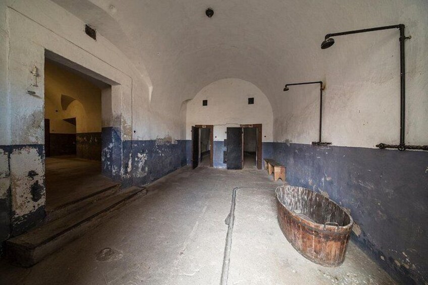 An abandoned building with a large bathtub, arched doorways, and peeling paint. 3